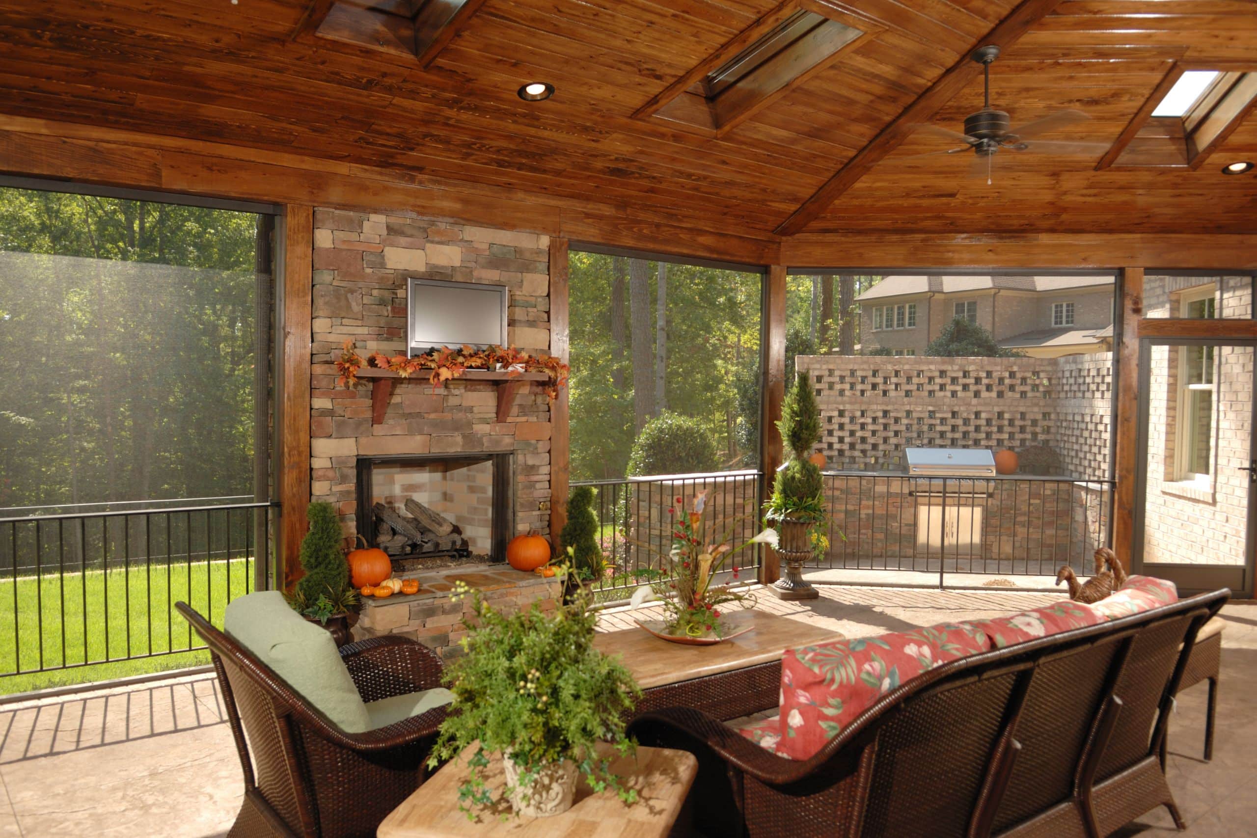 a screened porch with wood trim and a stone fireplace