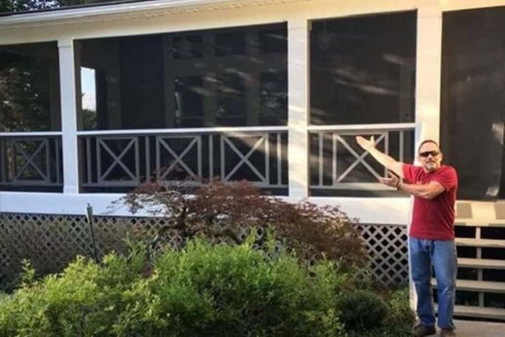 a DIY porch screen with a man standing in front of his project